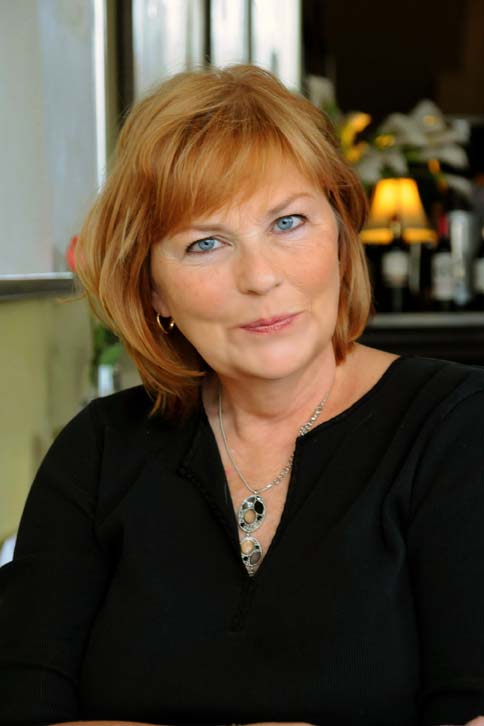 A woman with red hair and wearing black is smiling.