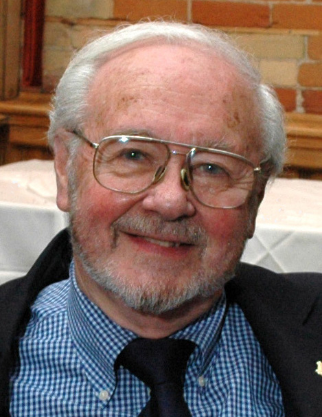 A man with glasses and a beard wearing a suit.