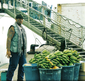 A man standing next to buckets of bananas.