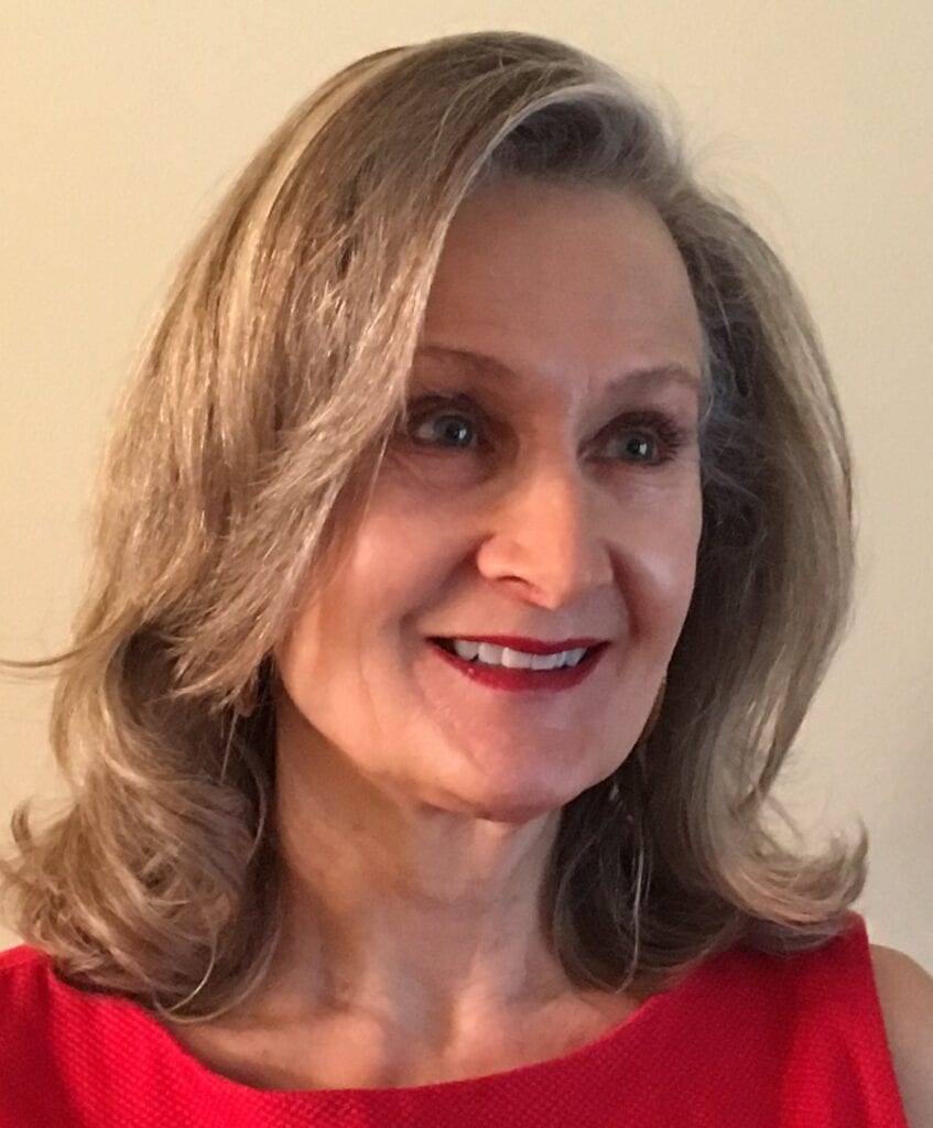 A woman with long hair wearing red is smiling.