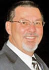 A man in suit and glasses smiling for the camera.