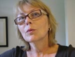 A woman with glasses is looking at the camera.