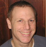 A man smiling for the camera with his head turned to the side.